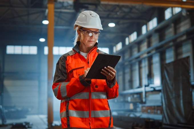 manufacturing-erp-system Une employé d'usine qui utilise le système ERP depuis sa tablette électronique.