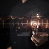 The concept of technological innovation represented by a businessman holding a light bulb.