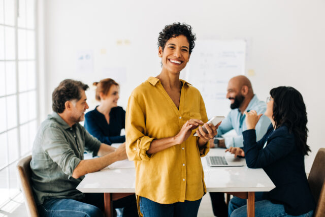 A smiling business leader surrounded by her managers, happy with her choice of ERP solution. the best ERP solution for your business