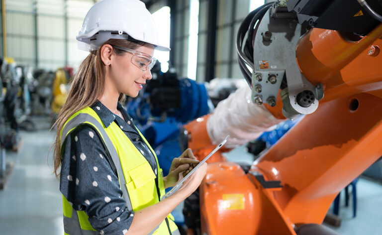 Female engineer installing software on industrial robotics.
