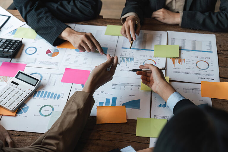 Businesspeople reviewing analytics, charts, and sticky notes together.
