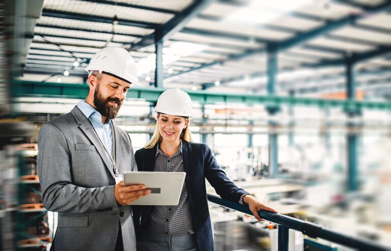 Engineers discussing a project with a tablet in a factory.